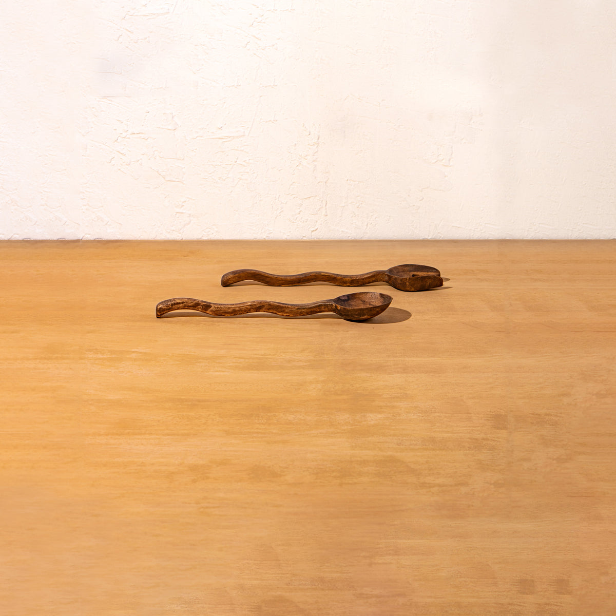 Pair of Wavy wooden salad servers lying on a surface