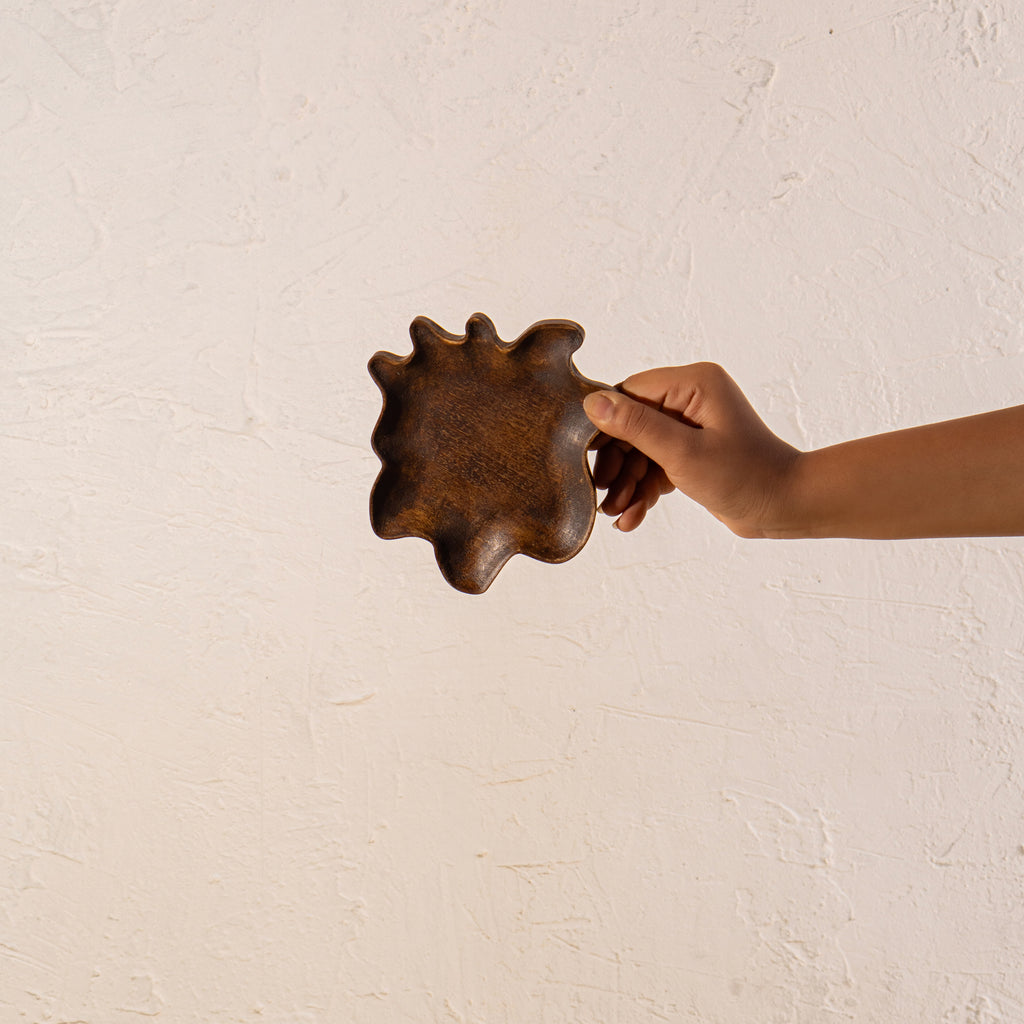 Wavy wooden spoon rest held in one hand